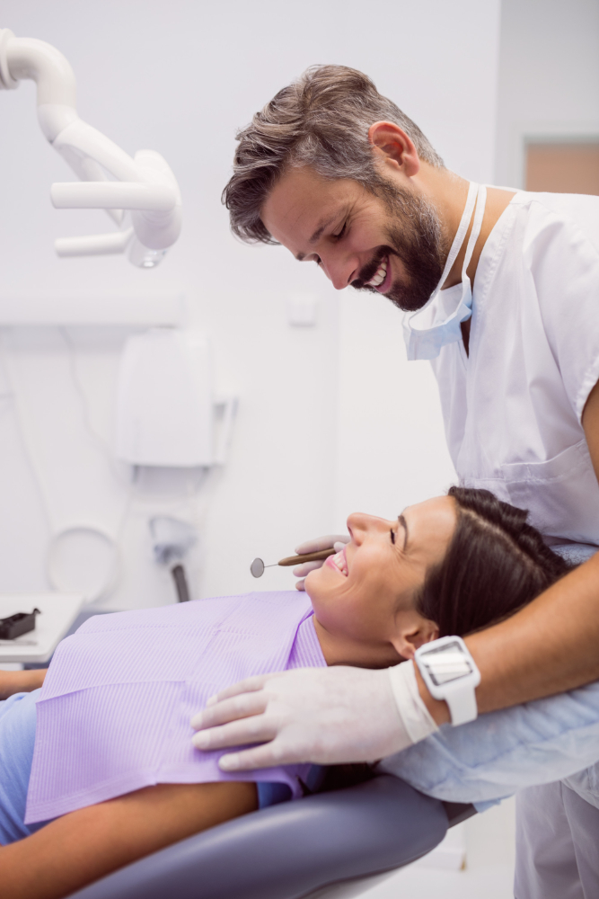 Dentist smiling while examining a patient during a dental cleaning